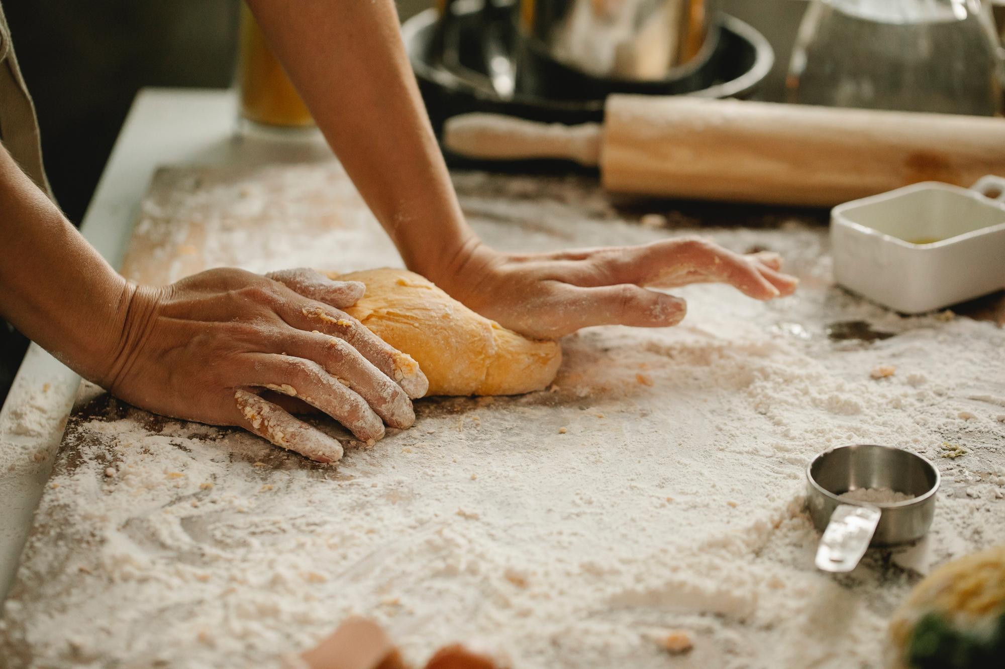 Hands kneading dough on wooden table